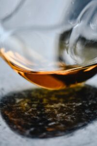 Artistic close-up of cognac in a curved glass reflecting on a marble surface.